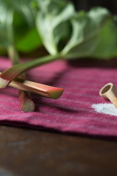 Feuilles de rhubarbe et sucre sur une table.